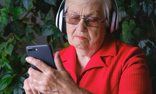 older woman listening to music on phone with headphones