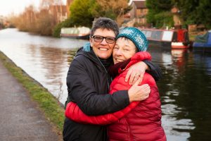 Two women having a hub beside canal