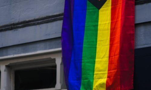 LGBTQ+ flag hanging from a window