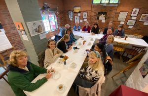 Action for Carers Volunteers sit around a table enjoying tea and chat at Watts Gallery